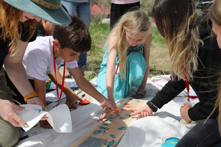 A group of students add their thumb prints to The Nest sign.