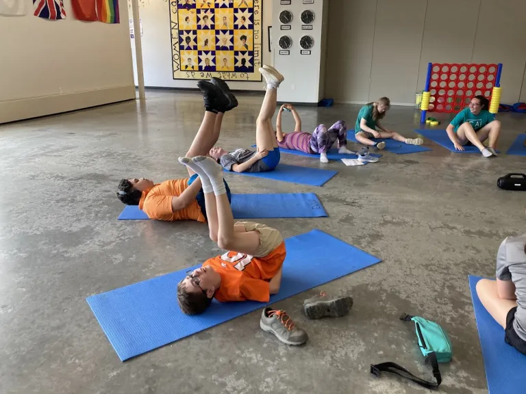 Amico campers doing exercises on a mat indoors