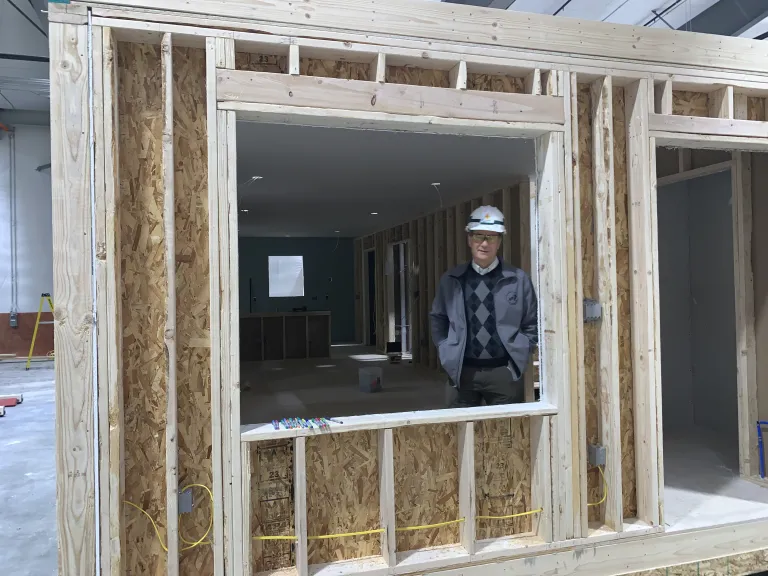 Kurt Firnhaber looking out of a window opening in a partially constructed home in the Boulder Mod factory.