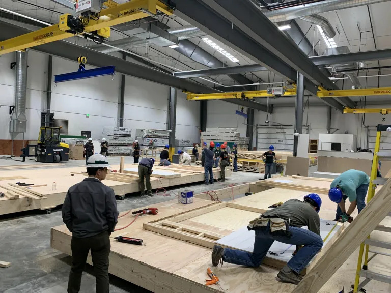 Student and volunteer workers working on modular homes in the Boulder Mod factory.