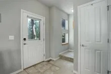 Entry foyer with tile flooring, a white door, and natural light.