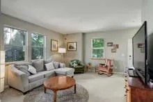 Spacious living room with two sofas, a TV, and large windows