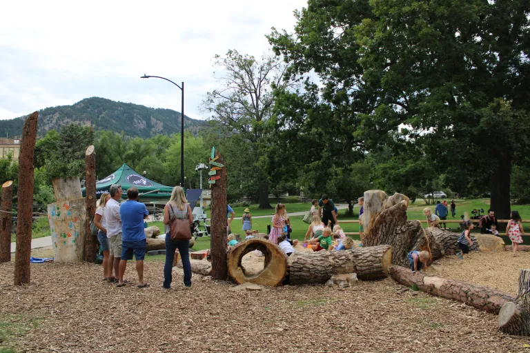 Nature play area log tunnel feature with children
