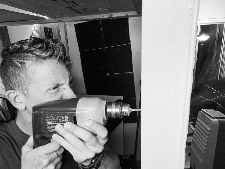 Andy using a drill to renovate a music studio. 
