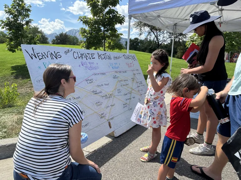 woman kneeling next to a sign with yard markers talking to kids