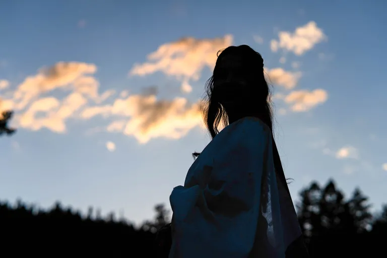 Silhouette of a woman looking off into a sunset. 