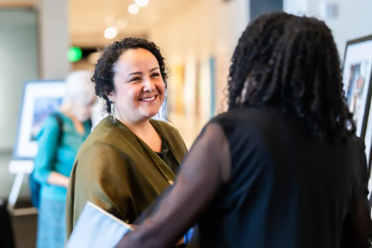 Ingrid Castro-Campos speaking with Alexis Miles from Motus Theater in the Dairy Arts Center lobby. 