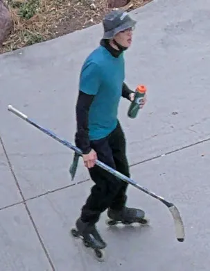 Right profile image of man in blue shirt, long sleeves, helmet and skates holding a hockey stick
