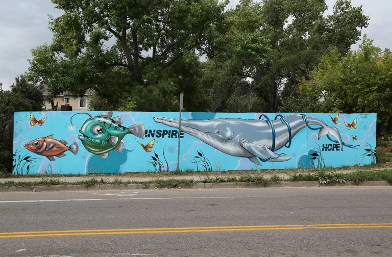 Mural of a whale and fish on a fence