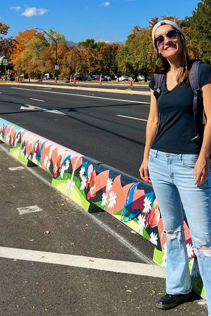 Artist Talia Swartz Parsell next to designs featured on tall concrete curbs along Baseline Road.