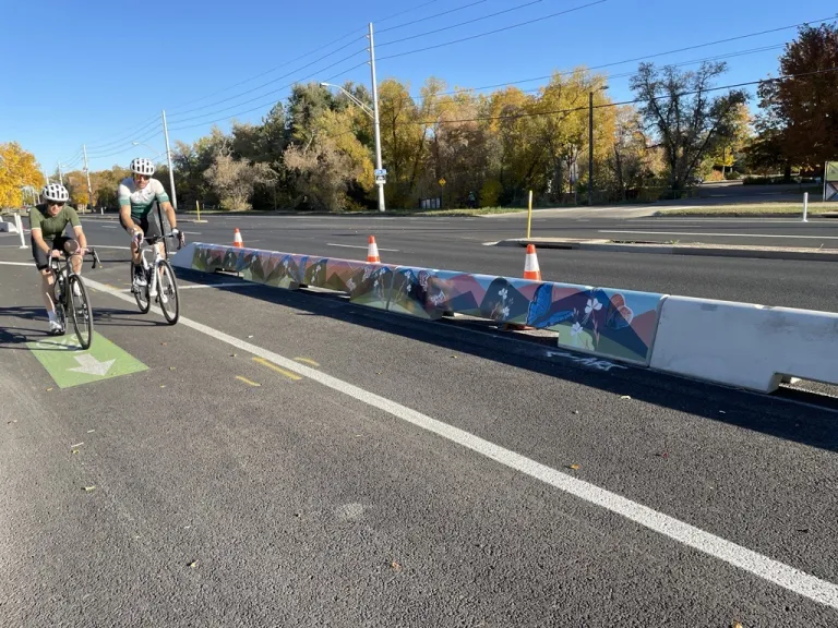 people biking next to decorated tall curbs along Baseline Road.