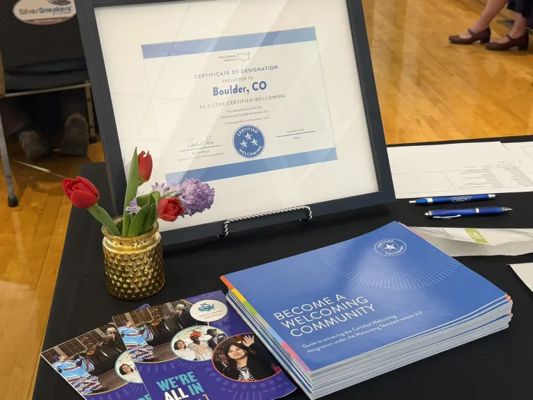 Certificate of designation framed on welcome table next to a pot of flowers and information packets