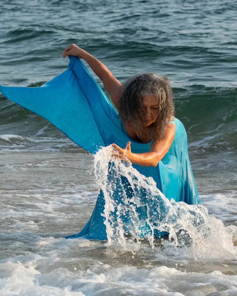 Afro-Brazilian dancer wearing a flowy blue dress in the waves 