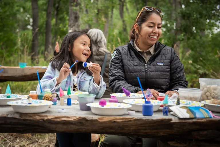 child and ranger painting rocks in park