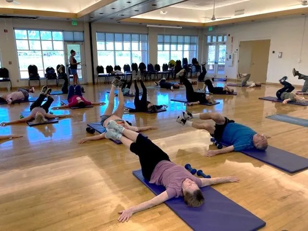 Older adults laying on yoga mats doing a fit and strong workout. 