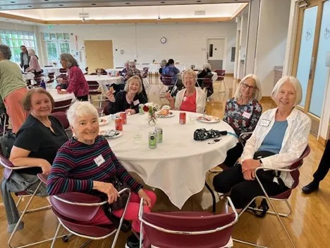 Group of older adult women sitting around a table at the OAS Spring Social. 