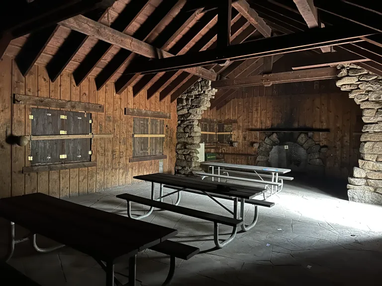 Inside Green Mountain Lodge, a rustic building with picnic tables and stone columns.