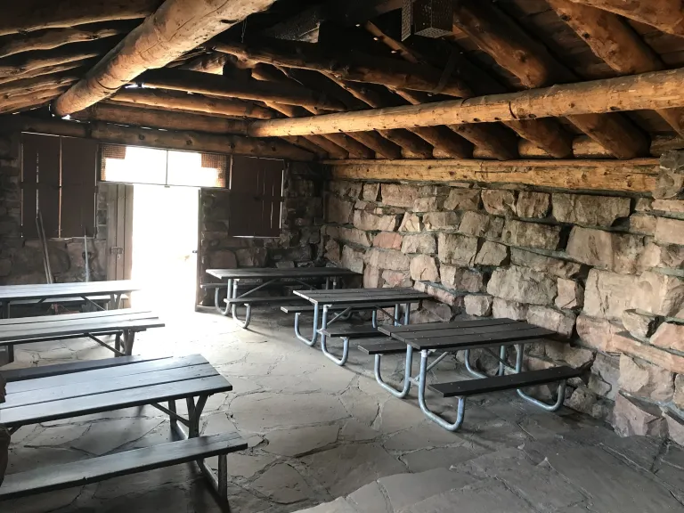 Six picnic tables inside the Halfway House, three on each side with a row down the middle.