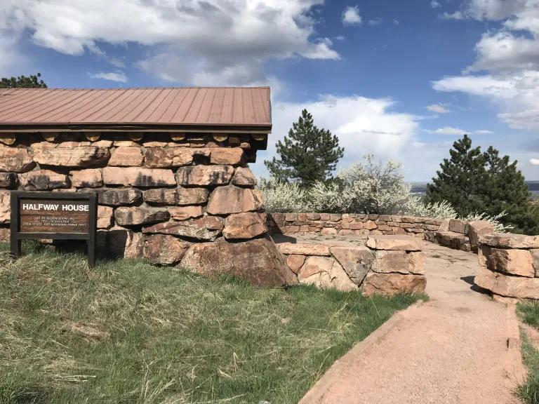A wide, gravel trail leads to the Halfway House flagstone patio, with the Halfway House on the left.