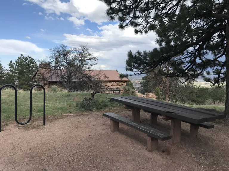 A picnic table and bike rack with the Halfway House behind.