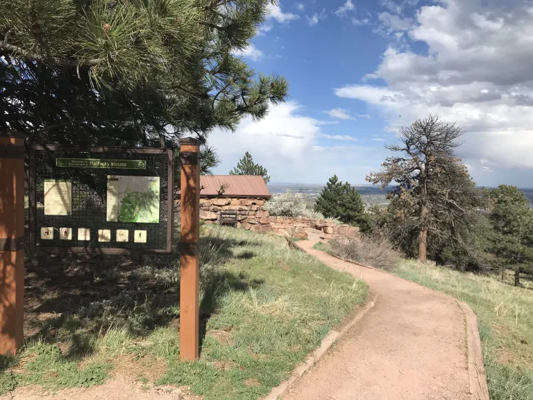 A gravel path leads to the Halfway House patio with peekaboo views of Boulder beyond.