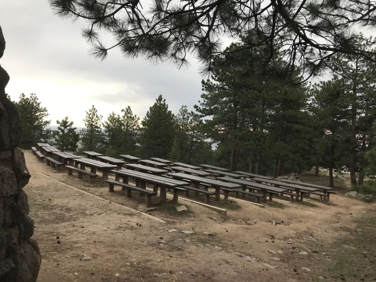 Rows of picnic tables heading slightly downhill, viewed from the doorway of the Stone Shelter.