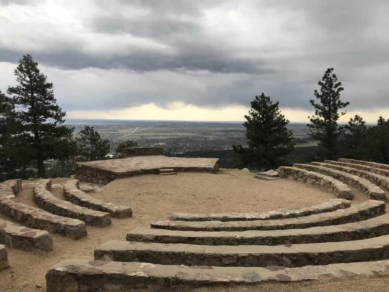 Stone seating circling down toward the center of Sunrise Amphitheater with Boulder down below.