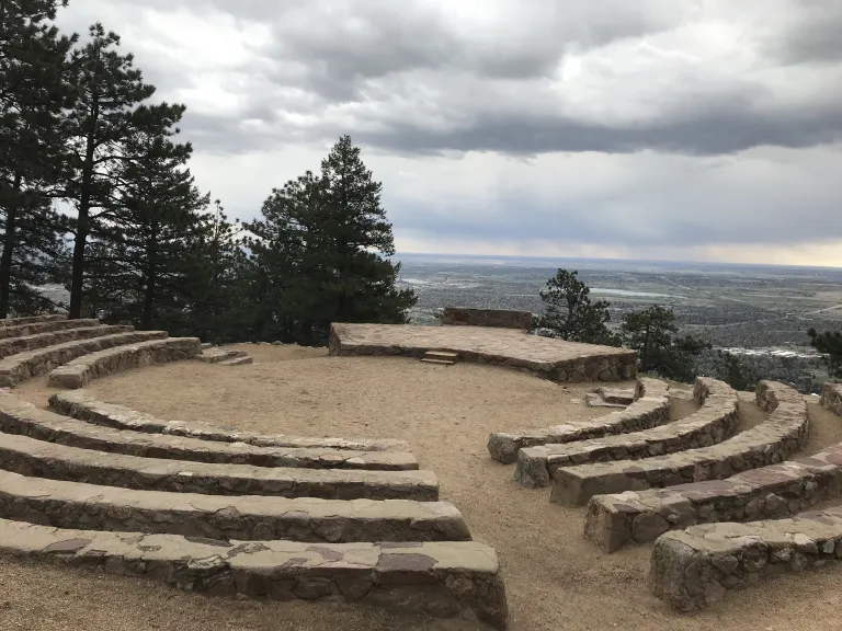 Stone seating circling down toward the center of Sunrise Amphitheater with Boulder down below.