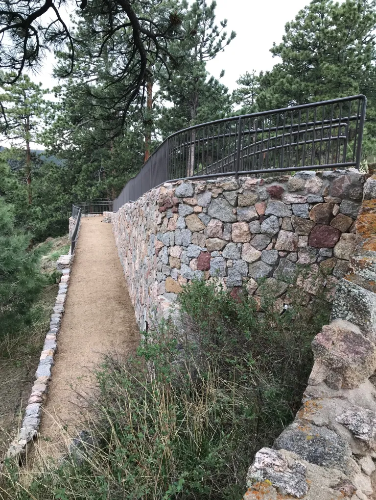 A dirt ramp goes down along a rock wall.