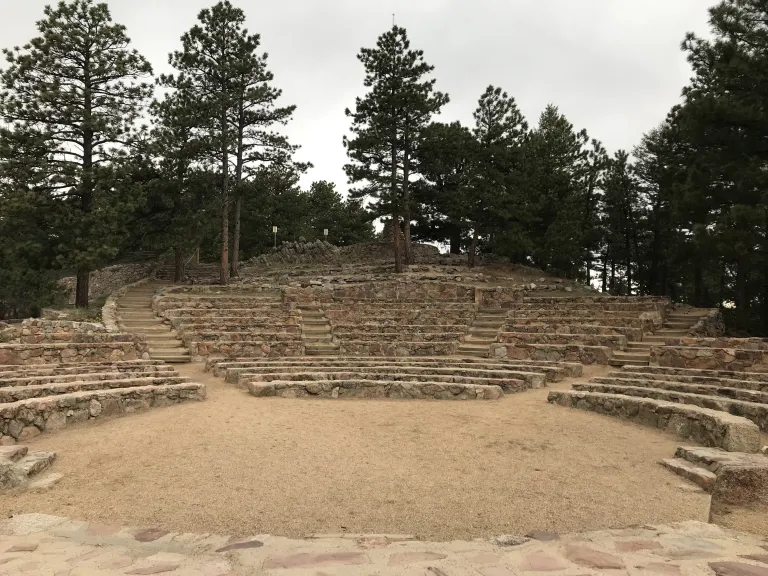 Standing on the edge of the stone stage, the Sunrise Amphitheater center circle is in front, then rows of stone seats circling behind.