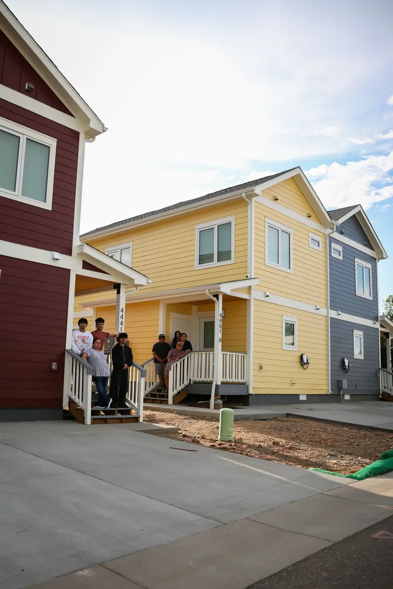 Families pose for a picture in front of their new BoulderMOD homes. 