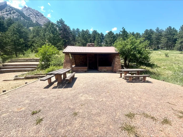 Front-on view of the Bluebell Shelter with picnic tables in front and the First Flatiron visible behind.