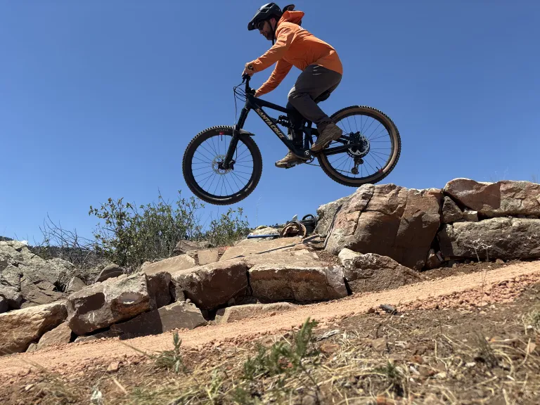 A mountain biker getting some air over a rock feature on the North Foothills Trail.