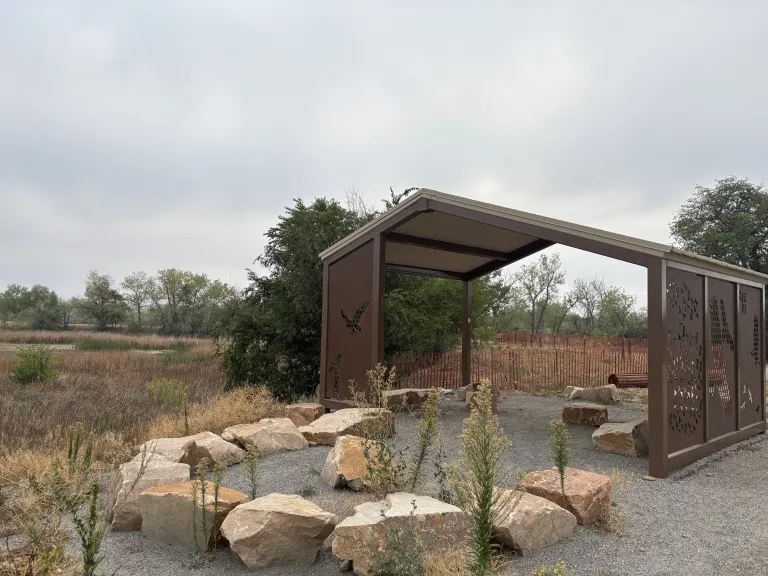 Beautiful shelter with carved metal sides and a rock seating area outside at Sawhill Ponds.