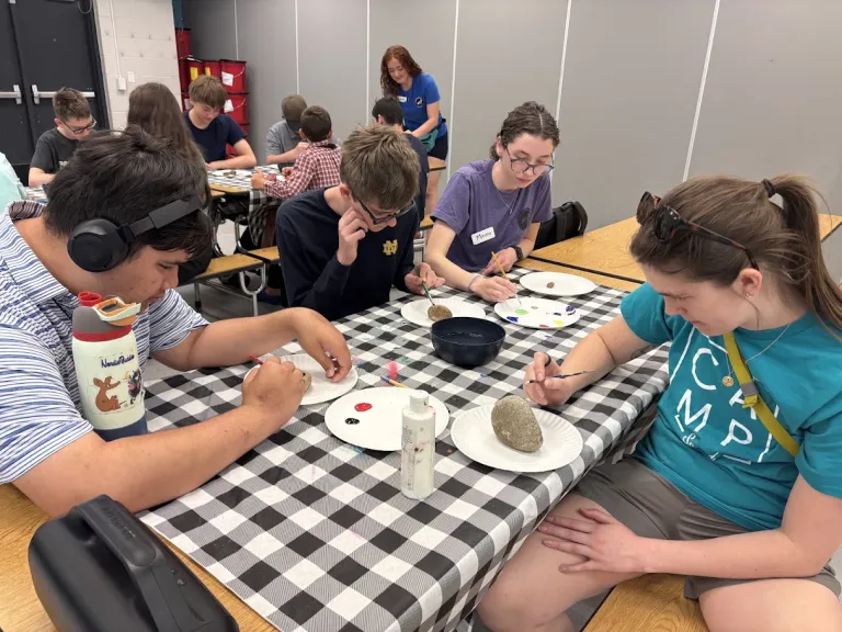 A group of children sitting around a table participating in an activity together. 