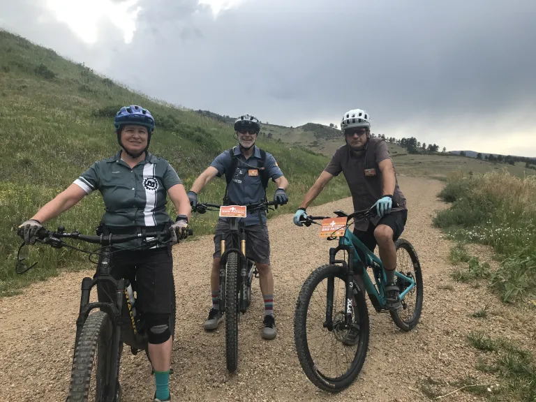 Three people on mountain bikes on a dirt trail.