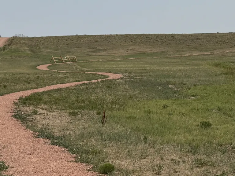 A gravel trail winding away through grasslands.