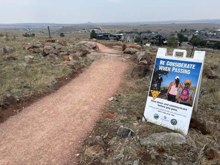 A sign next to North Foothills Trail stating: Be considerate when passing.