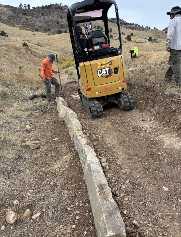 A small yellow construction vehicle working on a trail.