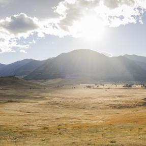 Open space south of Boulder. Sun glare peers out of the clouds above Boulder's mountain backdrop