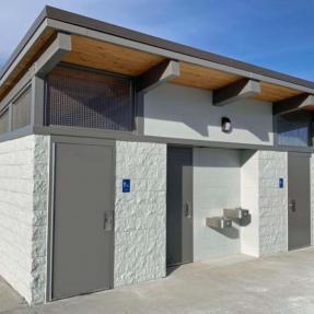 The white brick restroom building with an angled roof and water bottle filling station.