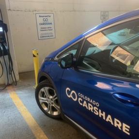A blue Chevy Bolt with a Colorado CarShare decal charges in a city of boulder parking garage