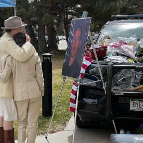 Two people embracing in front of Officer Talley memorial at Boulder Police Department