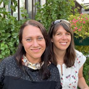 Two people posing for photo in front of garden