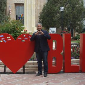 Man making a heart with his hands in front of an 'I [heart] Boulder' sign