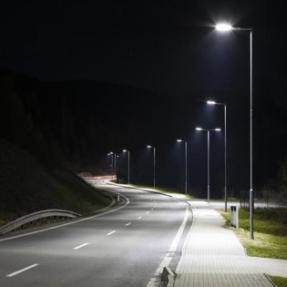 LED Streetlights shine on a two-way road with an adjacent sidewalk