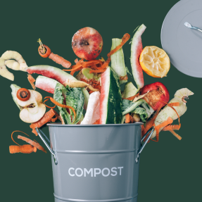 Food scraps spilling out of a metal compost container. 