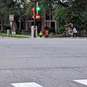 People biking across the road. There is no marked crosswalk where they cross.