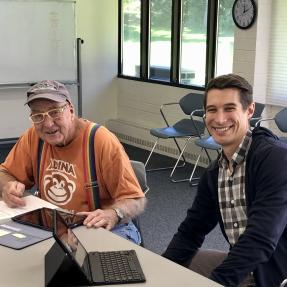 An older adult services volunteer helping a community member with a tablet