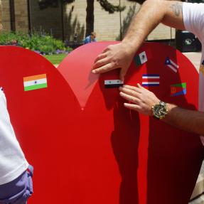 Person putting flag stickers on a red heart in an 'I (heart symbol) Boulder' sign
